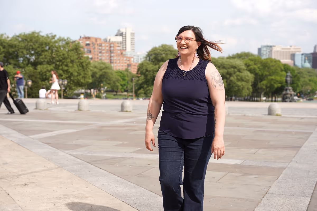 brunette lady with glasses walking in an outdoor urban setting
